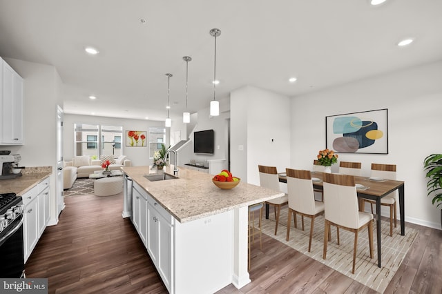 kitchen featuring a kitchen island with sink, hanging light fixtures, wood-type flooring, and white cabinets