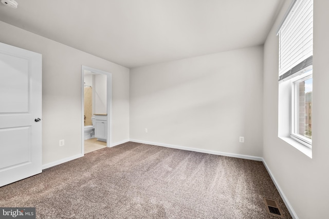 unfurnished bedroom featuring light carpet and connected bathroom