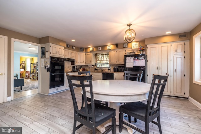 dining room featuring sink, light hardwood / wood-style floors, and a notable chandelier