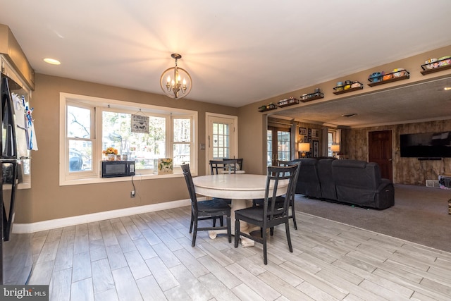 dining space with a healthy amount of sunlight, light wood-type flooring, and a chandelier