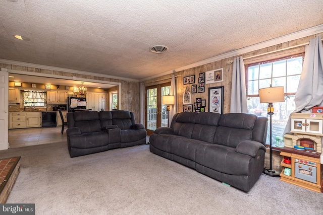 living room with a textured ceiling, ornamental molding, and light carpet