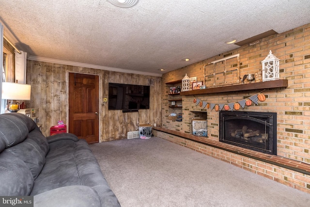 carpeted living room with a textured ceiling, wooden walls, a brick fireplace, and crown molding