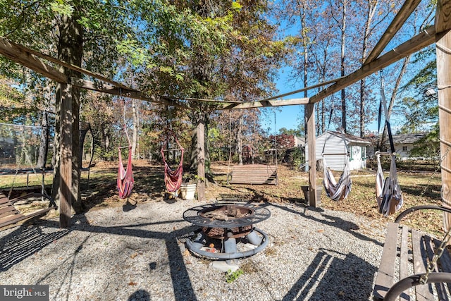 view of yard with a storage shed, a trampoline, and an outdoor fire pit