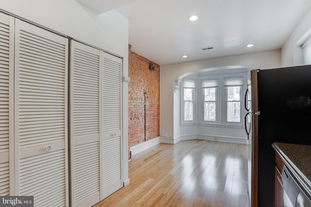 kitchen featuring stainless steel appliances, light hardwood / wood-style flooring, and brick wall