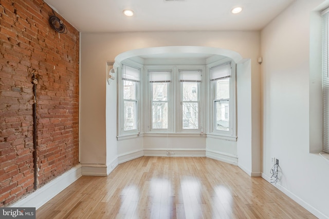 spare room featuring light hardwood / wood-style floors and brick wall