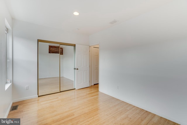 unfurnished bedroom with light hardwood / wood-style flooring and a closet