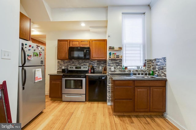 kitchen featuring sink, tasteful backsplash, black appliances, and light hardwood / wood-style flooring