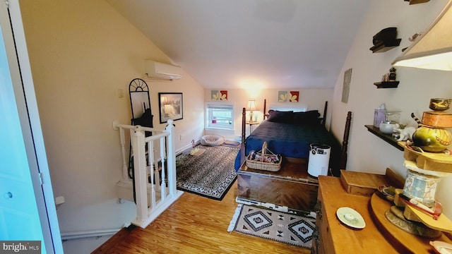 bedroom with light hardwood / wood-style flooring, lofted ceiling, and a wall mounted air conditioner