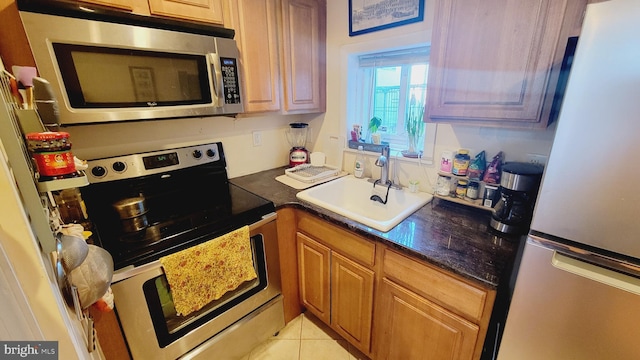 kitchen with stainless steel appliances, sink, and light tile patterned flooring