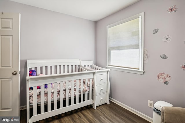 bedroom featuring a nursery area and dark wood-type flooring