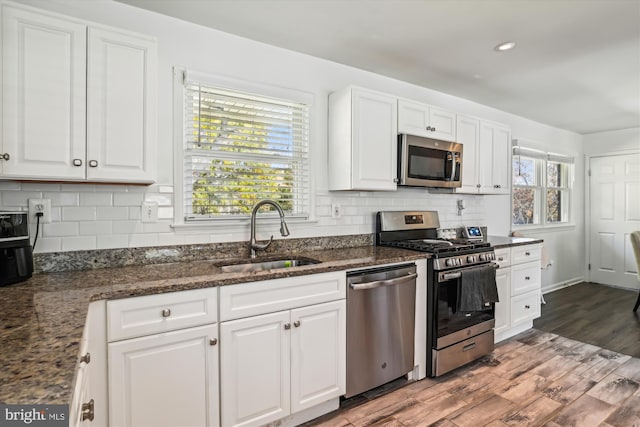 kitchen with stainless steel appliances, a wealth of natural light, white cabinets, and sink