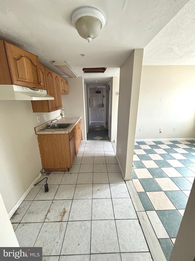 kitchen with light tile patterned flooring, a textured ceiling, and sink