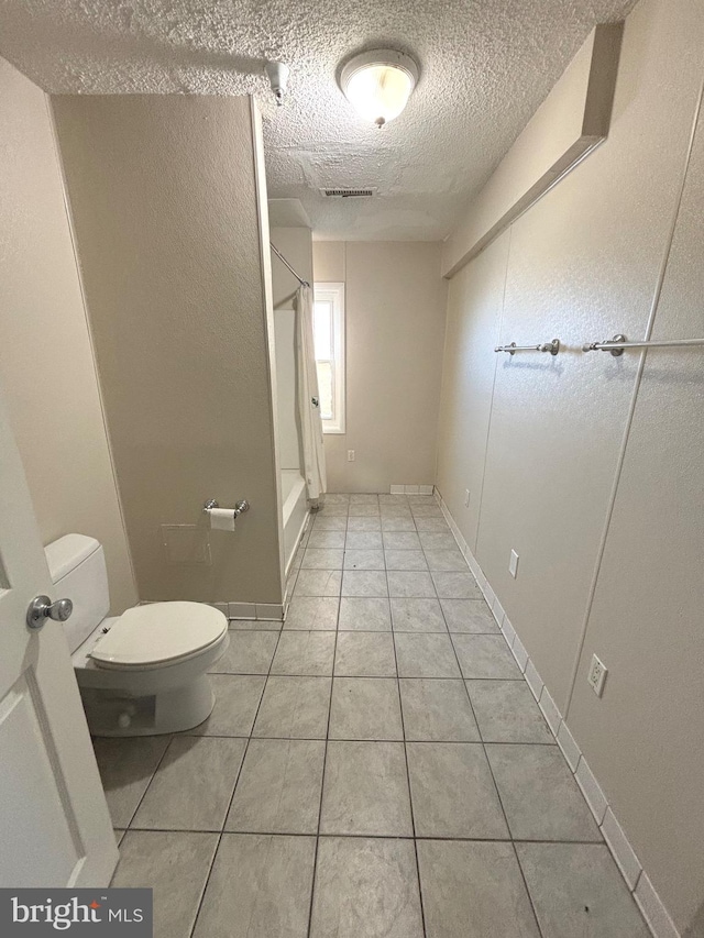 bathroom featuring toilet, a textured ceiling, tile patterned flooring, and a shower with shower curtain