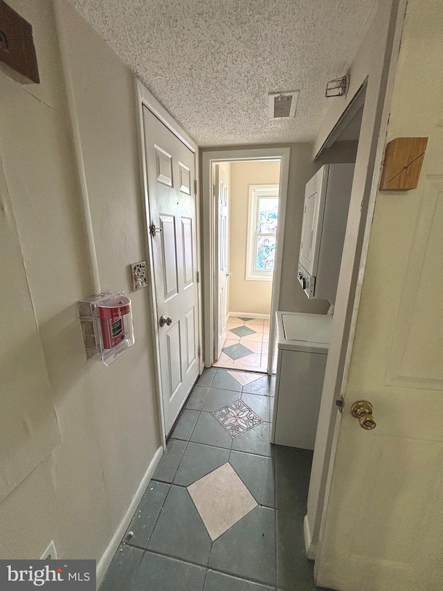 corridor with a textured ceiling and light tile patterned flooring