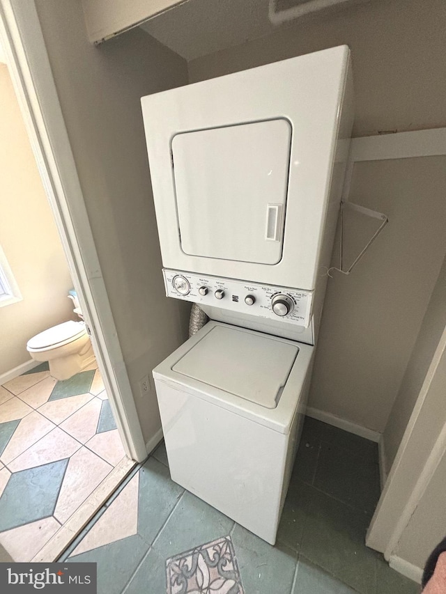 washroom featuring stacked washing maching and dryer and light tile patterned floors