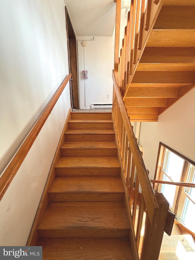 stairs with hardwood / wood-style floors and a baseboard heating unit