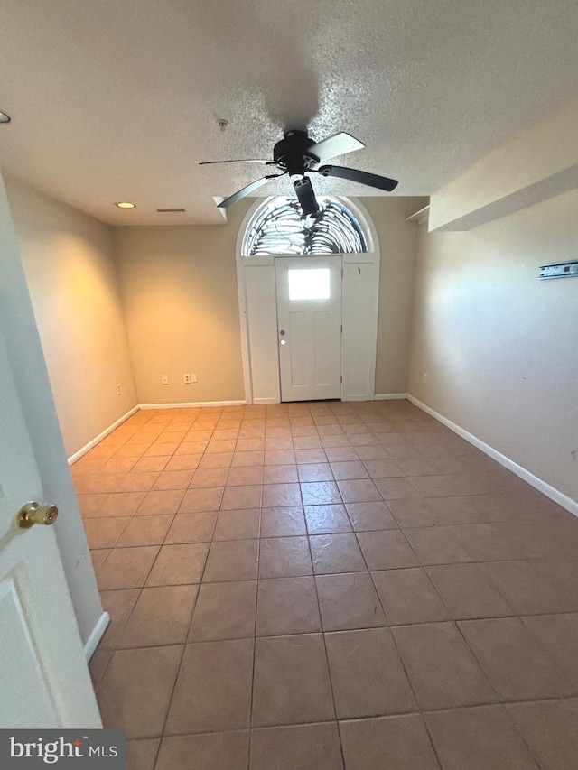 tiled foyer featuring a textured ceiling and ceiling fan