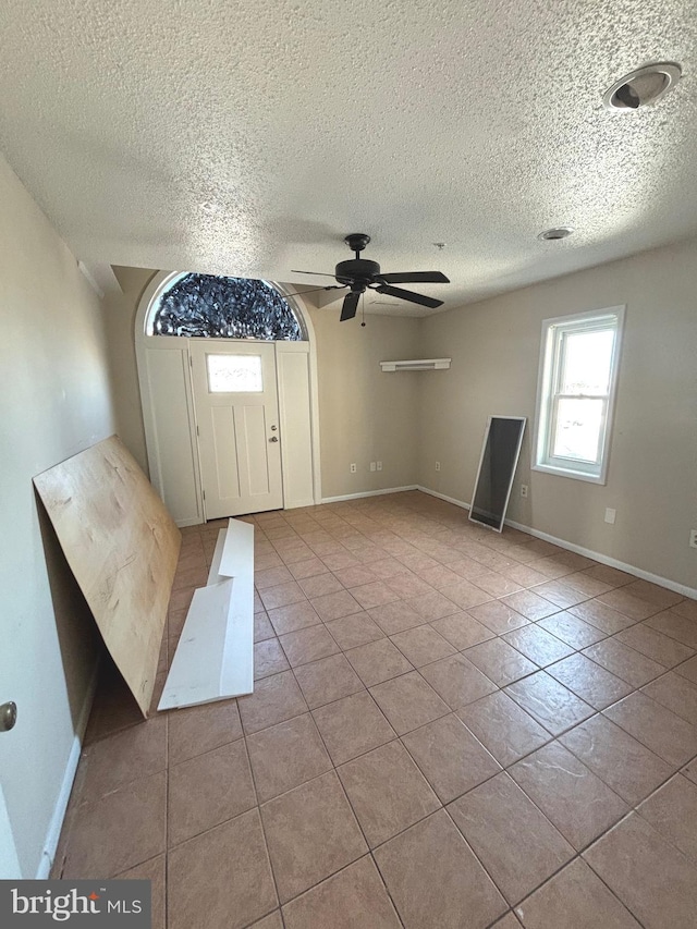 foyer entrance featuring light tile patterned flooring, a textured ceiling, and ceiling fan