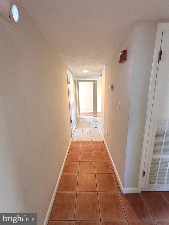 hallway with tile patterned floors and a textured ceiling