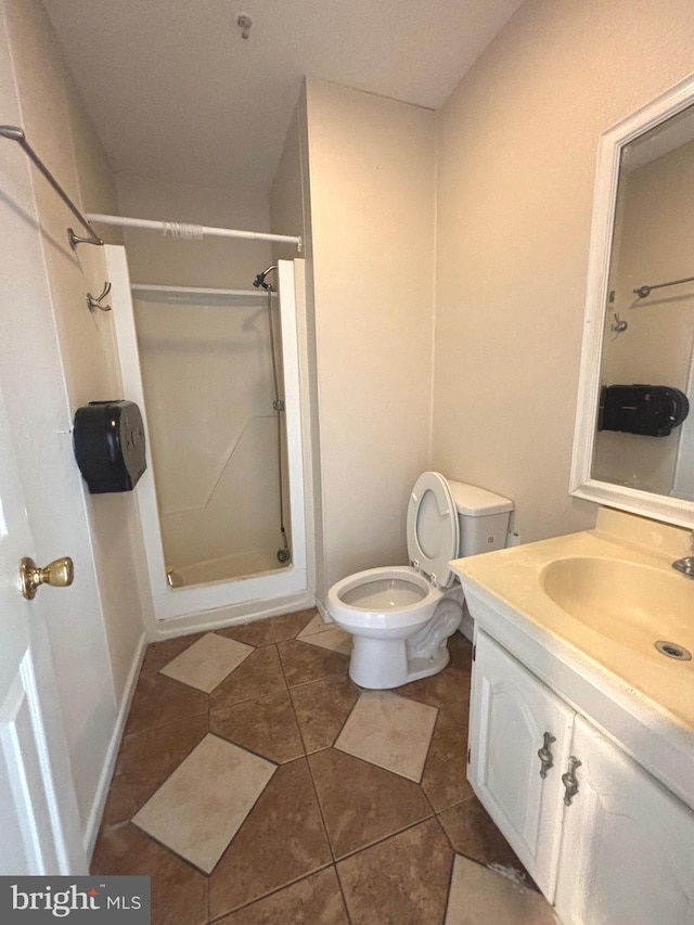 bathroom featuring vanity, walk in shower, toilet, and tile patterned flooring