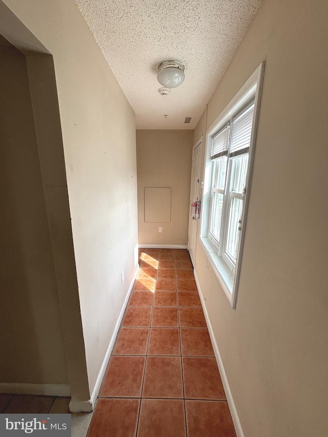 hallway featuring dark tile patterned floors and a textured ceiling