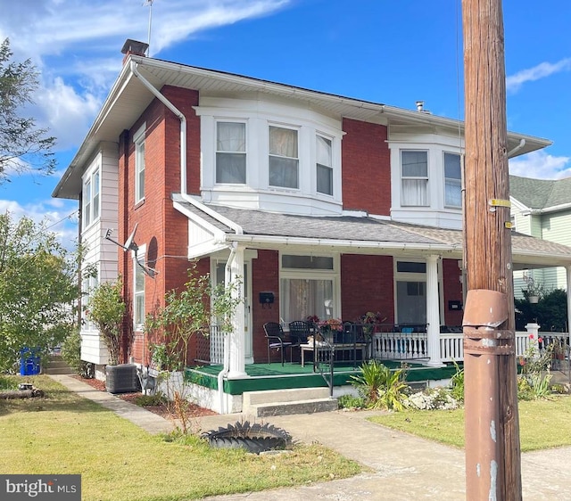 view of front facade featuring central air condition unit, a front yard, and a porch