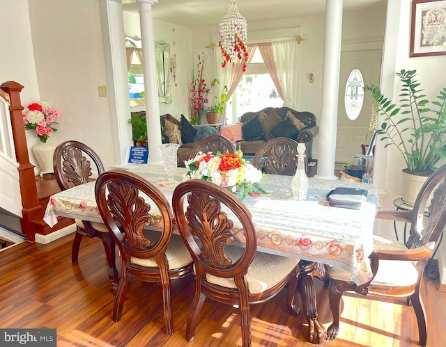 dining space featuring hardwood / wood-style flooring, decorative columns, and a chandelier