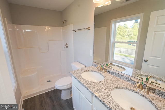 bathroom featuring toilet, hardwood / wood-style floors, vanity, and a shower