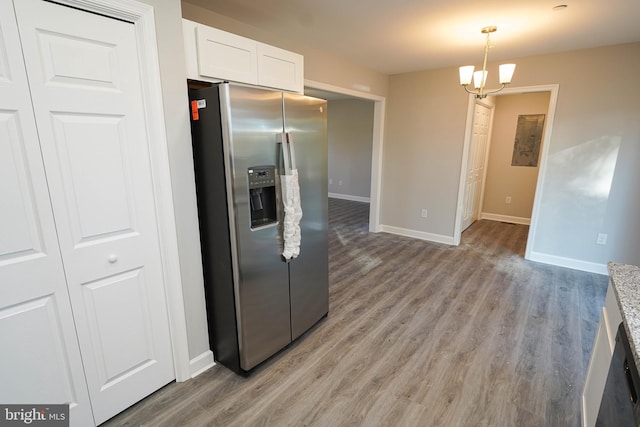 kitchen with white cabinetry, light hardwood / wood-style floors, pendant lighting, stainless steel fridge with ice dispenser, and an inviting chandelier