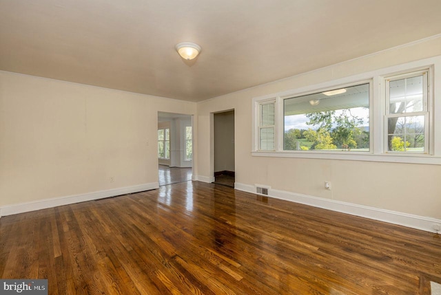 empty room with a wealth of natural light and dark hardwood / wood-style flooring