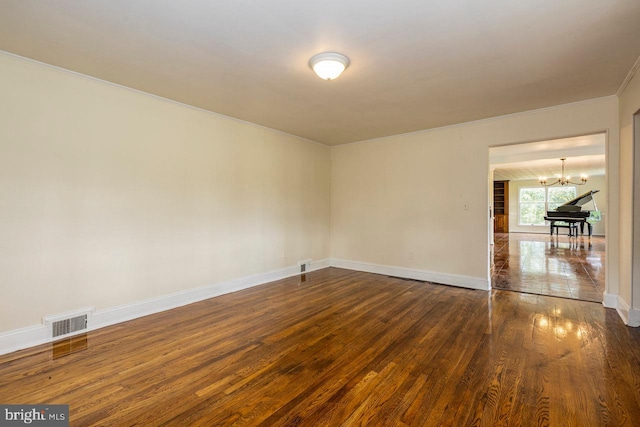 unfurnished room with dark hardwood / wood-style floors, ornamental molding, and an inviting chandelier