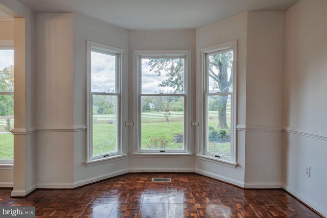 unfurnished room featuring dark parquet floors and a wealth of natural light