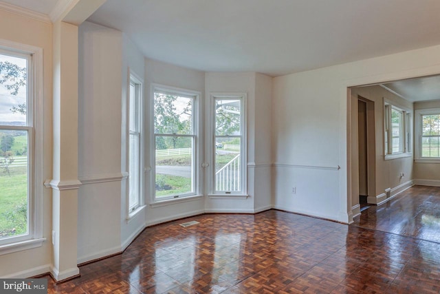 unfurnished room featuring dark parquet flooring, crown molding, and plenty of natural light