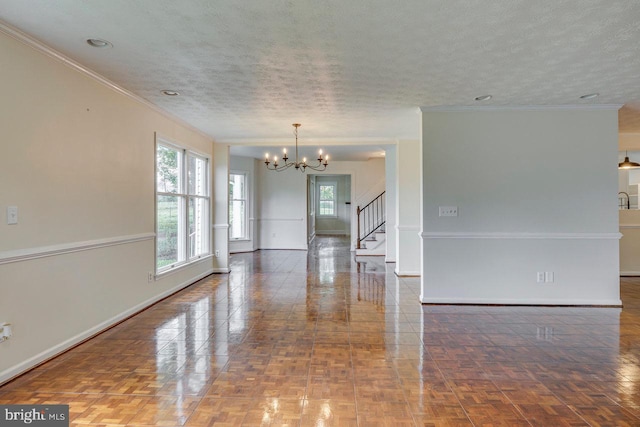 spare room featuring dark parquet floors, a textured ceiling, an inviting chandelier, and ornamental molding