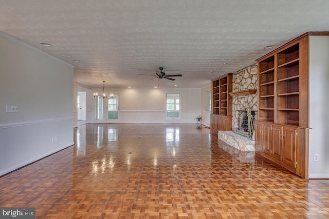 unfurnished living room featuring a fireplace, built in shelves, a textured ceiling, and crown molding