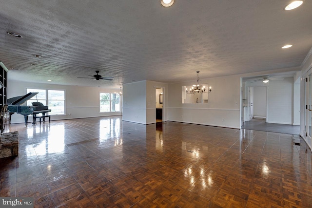 unfurnished living room featuring ceiling fan with notable chandelier and a textured ceiling