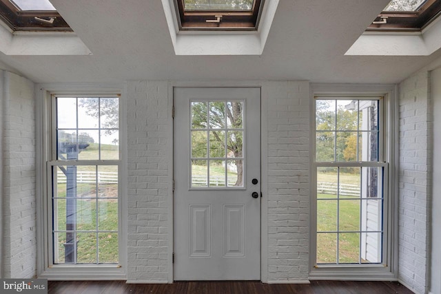 doorway to outside featuring a skylight, dark hardwood / wood-style flooring, and brick wall