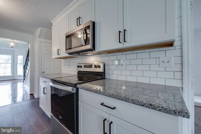 kitchen with white cabinets, dark hardwood / wood-style floors, light stone countertops, and appliances with stainless steel finishes