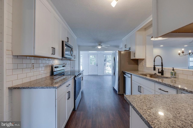 kitchen featuring appliances with stainless steel finishes, a textured ceiling, white cabinetry, and sink