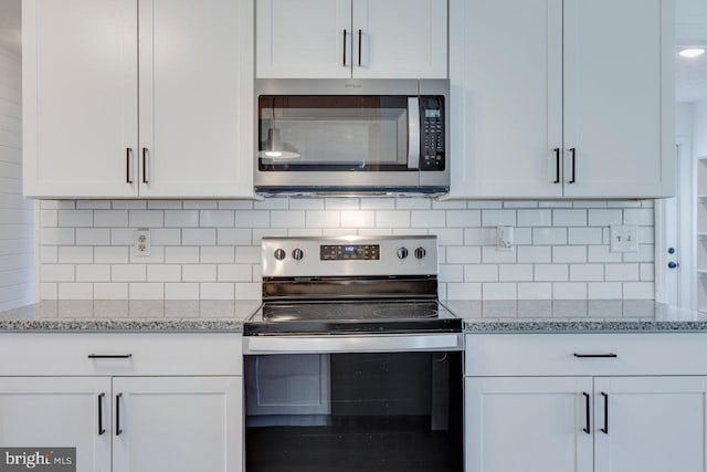 kitchen featuring decorative backsplash, light stone counters, white cabinets, and appliances with stainless steel finishes