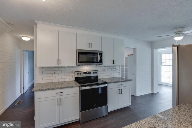 kitchen featuring white cabinetry, wooden walls, stainless steel appliances, and dark hardwood / wood-style floors