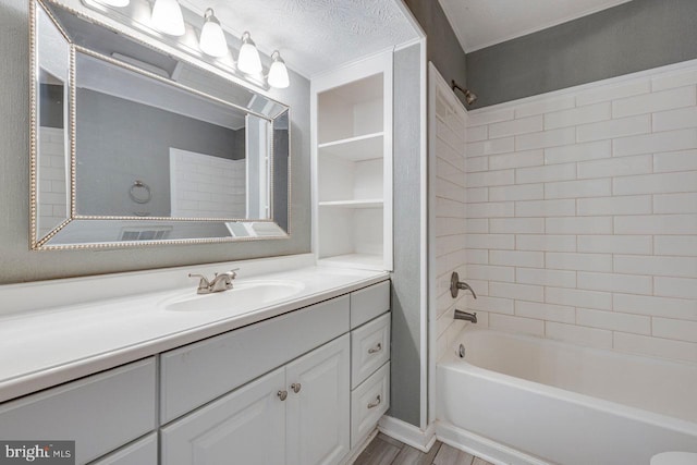 bathroom featuring vanity, wood-type flooring, a textured ceiling, and tiled shower / bath