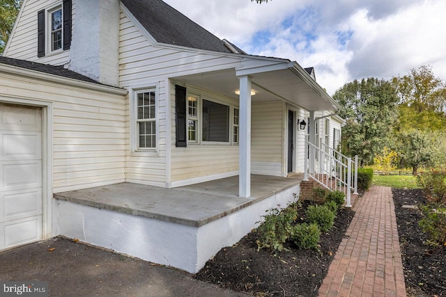 view of side of property featuring a garage and covered porch