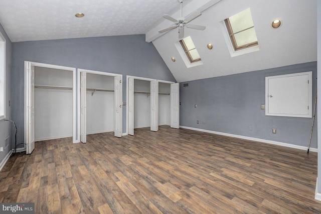 unfurnished bedroom with high vaulted ceiling, a skylight, dark hardwood / wood-style floors, beamed ceiling, and multiple closets