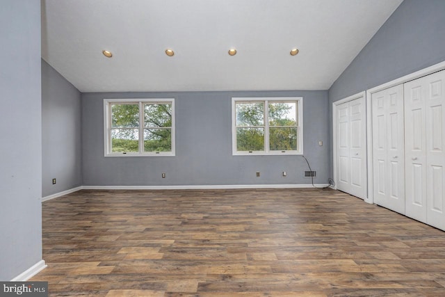 unfurnished bedroom featuring dark hardwood / wood-style flooring, multiple windows, and lofted ceiling