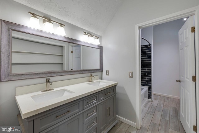 bathroom featuring vanity, bathing tub / shower combination, vaulted ceiling, a textured ceiling, and wood-type flooring