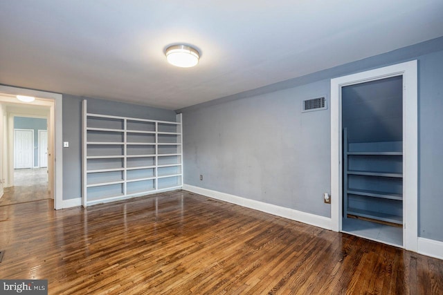 unfurnished room with built in shelves and hardwood / wood-style flooring