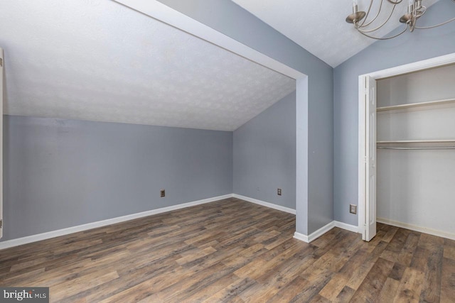 bonus room featuring a notable chandelier, dark hardwood / wood-style flooring, lofted ceiling, and a textured ceiling