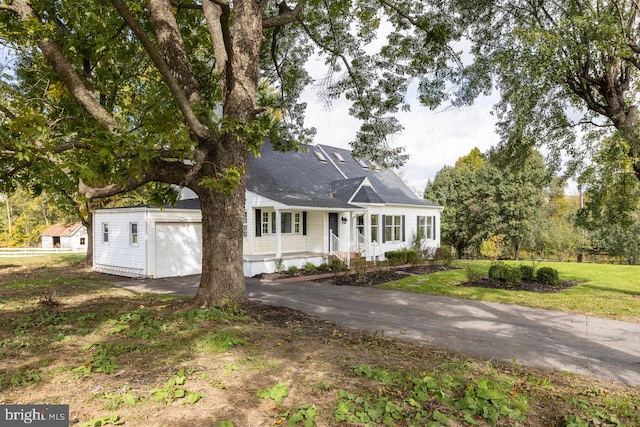 view of front of house featuring a front yard, a garage, and covered porch