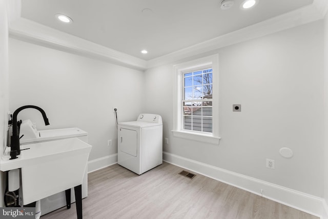 laundry room featuring ornamental molding, washer / dryer, sink, and light hardwood / wood-style flooring